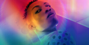 Queer nigerian person standing in an array of bright colors