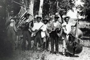 6 Black men dressed in suits standing in a field playing instruments